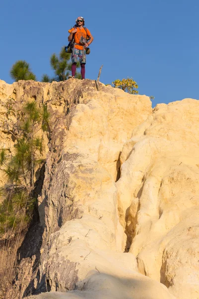 Turista com mochila em pé no topo de uma colina e desfrutando da vista para o mar por do sol — Fotografia de Stock