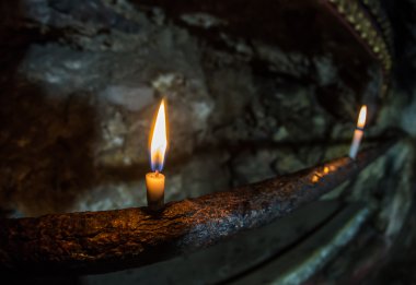 Siyah arkaplanda parlak bir mum yanıyor.