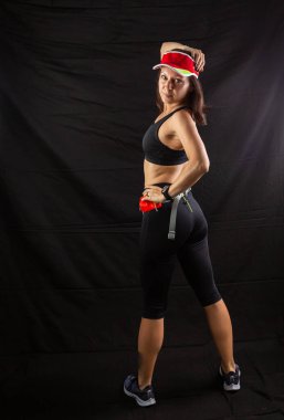 Stüdyoda siyah arka planda poz veren koşucu üniformalı güzel kızıl kız.