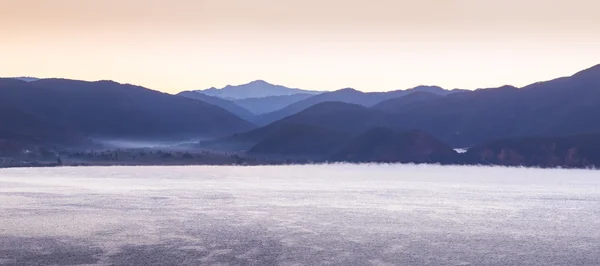 Nascer do sol brilhante no lago sobre o qual o vapor sobe — Fotografia de Stock