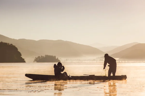 Fishermen at dawn on the mountain lake in a boat — Stock Photo, Image