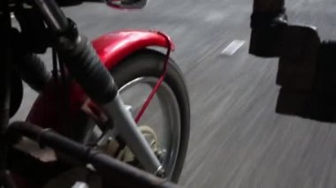 Motorcu kız bir motosiklet sürme. Alt görünümü ayakları ve deri çizmeler. Arka tekerlek üzerinde odaklanmak.