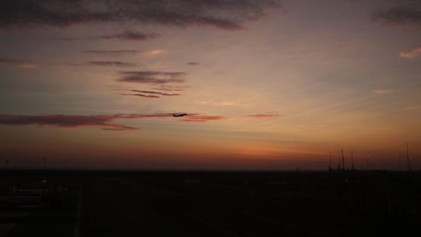 Passagierflugzeug fliegt bei Sonnenuntergang über Startbahn vom Flughafen — Stockvideo