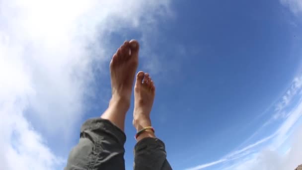 Ontspannen en de blote voeten de lucht in laten gaan in de zon. — Stockvideo