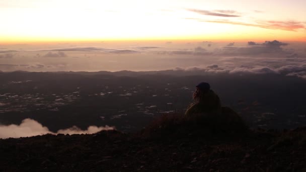 Turysta odpoczynku na szczycie skały i zachód słońca — Wideo stockowe