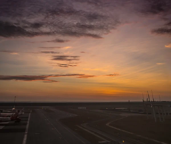 Пассажирский самолет пролетает над взлетно-посадочной полосой из аэропорта на закате — стоковое фото