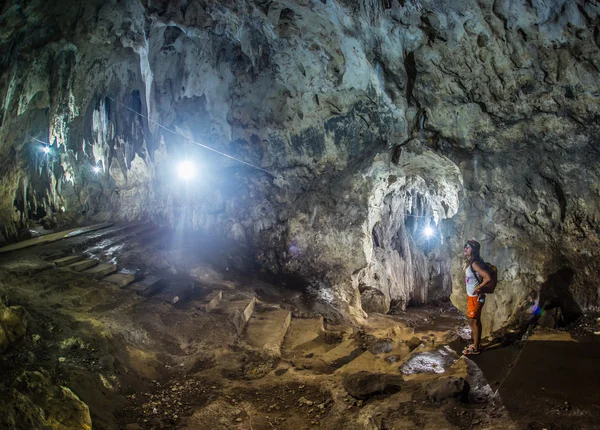 Junge Frau mit Rucksack erkundet Höhle — Stockfoto