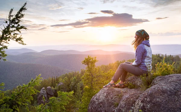 年轻的女人坐在岩石上，看向地平线 — 图库照片