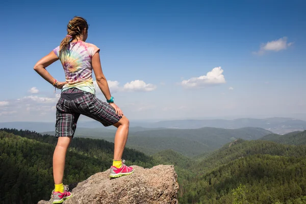 Junge Frau sitzt auf einem Felsen und blickt zum Horizont — Stockfoto