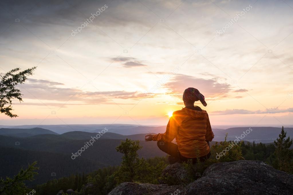 man meditating on a rock