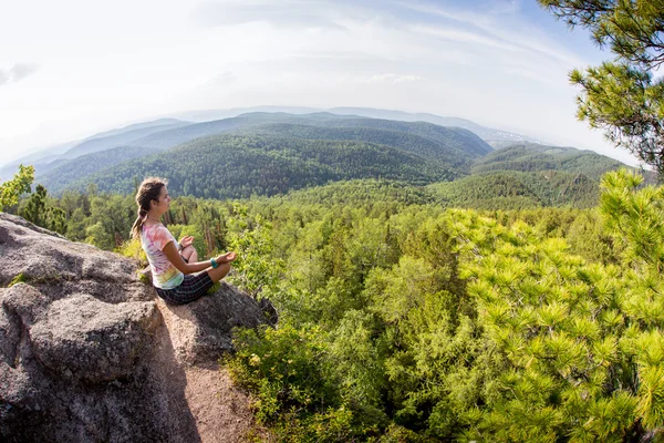Молодая женщина-йога сидит медитация на горной вершине скалы — стоковое фото