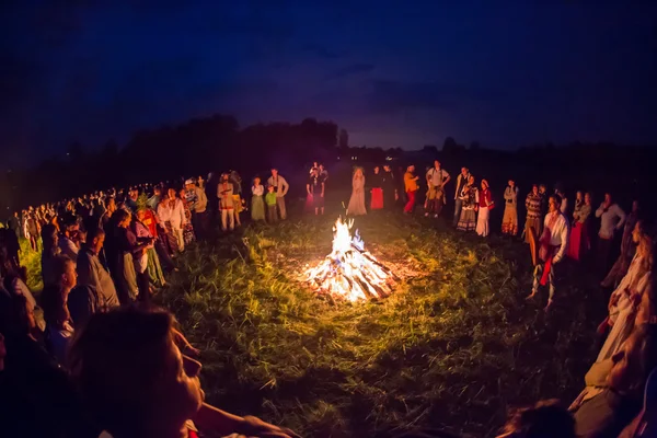 As pessoas celebram o feriado e a dança russa em um círculo em torno do fogo sagrado — Fotografia de Stock