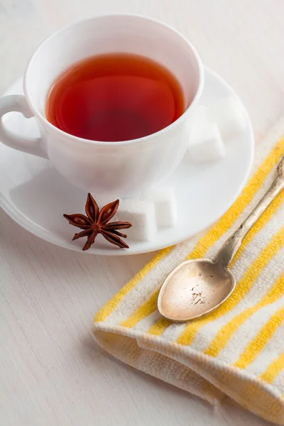 Cup of tea with teaspoon on kitchen towel — Stock Photo, Image