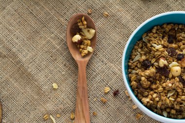 Granola kahvaltı tuval masa örtüsü üzerinde tahta kaşıkla yuvarlak mavi seramik kase