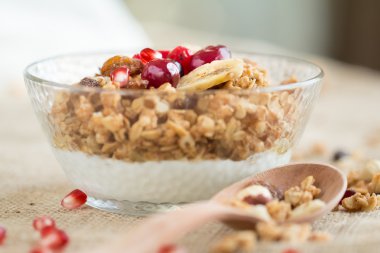 Kahvaltı kase kuru müsli ve gri tuval masa örtüsü üzerinde tahta kaşıkla kırmızı meyveler