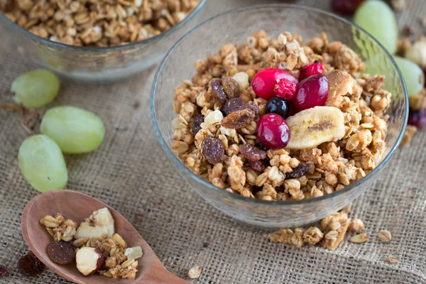 Duas tigelas de café da manhã de muesli seco, queijo cottage e bagas vermelhas com colher de madeira em pano de mesa de lona cinza — Fotografia de Stock