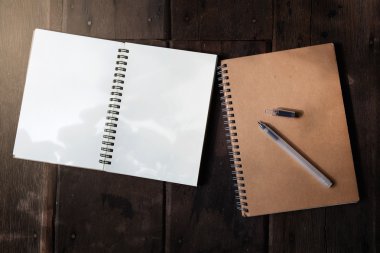 Ahşap arka plan üstünde kalem ve geri dönüşüm defter