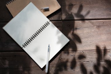 Ahşap arka plan üstünde kalem ve geri dönüşüm defter