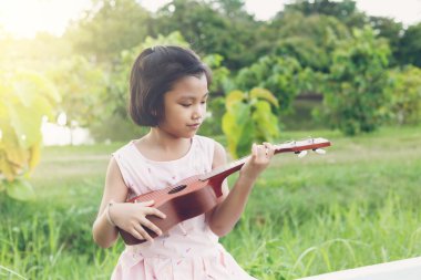 Oturma sevimli bir kız ve onun oyun akustik guitalele ağaç