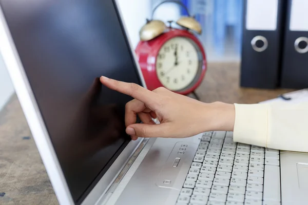 Woman hand and her finger touch screen on monitor a laptop on a