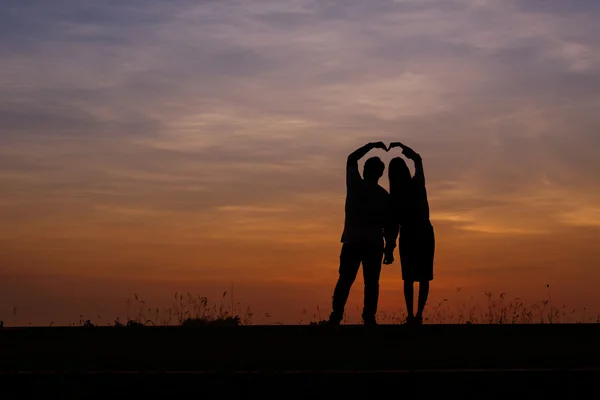 Silhouette man and woman with beautiful the sky at sunset
