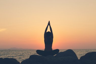 Siluet kadın. o plajda SU'da kayada yoga egzersiz