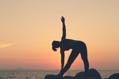 Siluet kadın. o plajda SU'da kayada yoga egzersiz