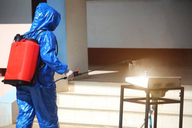 Steril giysili sağlık çalışanları COVID-19 virüsünü önlemek için kimyasal püskürtüyorlar. Ofis binalarında ya da tehlikeli bölgelerde yeni bir dezenfektan formülü kullanarak insanları Corona 2019 'dan korumak..