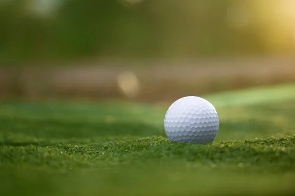 Golf ball is on a green lawn in a beautiful golf course with morning sunshine.Ready for golf in the first short.Sports that people around the world play during the holidays for health.