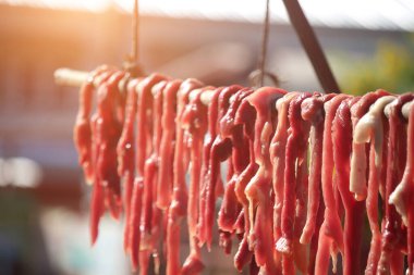 Korkulukta dilimlenmiş domuz ve biftek. Satılık ya da tüketim için güneşe maruz kalarak uzun süre yiyecek depolanacak..