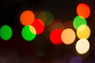 Gecenin karanlığında bulanık renkli bokeh ışıkları. Grafik tasarımı için arka planlar, Noel tatilleri, Yeni Yıl festivalleri veya kutlamalar.