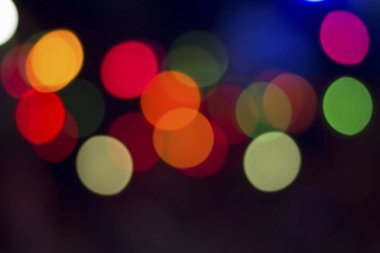 Gecenin karanlığında bulanık renkli bokeh ışıkları. Grafik tasarımı için arka planlar, Noel tatilleri, Yeni Yıl festivalleri veya kutlamalar.