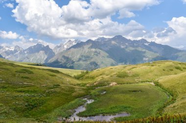 Svaneti bölgesinde yaz dağı manzarası, Gürcistan, Asya. Arka planda karlı dağlar var. Üzerinde bulutlar olan mavi gökyüzü. Gürcistan 'a seyahat