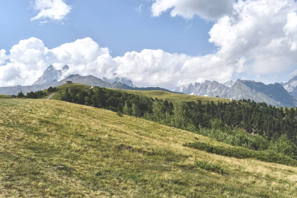 Nyári hegyvidéki táj közelében Mestia, Szvaneti régió, Grúzia, Ázsia. Snowcapapped hegyek a háttérben. Kék ég, felhőkkel felettünk. Grúzia úti célja — Stock Fotó