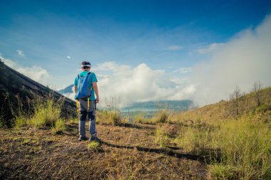Sırt çantası altında bekleyen üst bir dağ ve Vadi Manzaralı zevk ile genç adam
