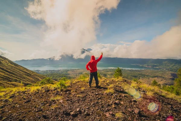 Joven de pie con las manos levantadas en la cima de una montaña y disfrutando de la vista del valle — Foto de Stock