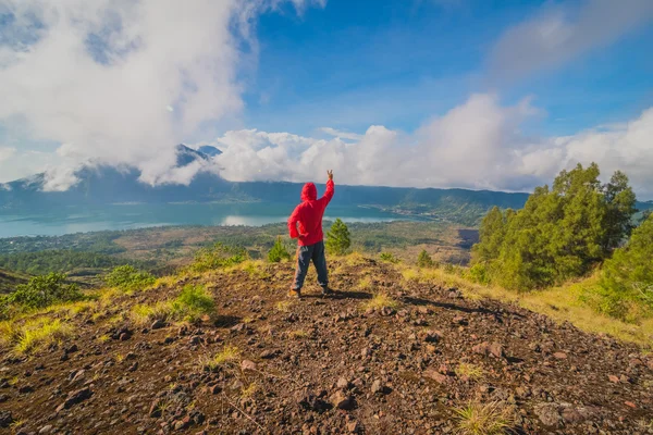 Joven de pie con las manos levantadas en la cima de una montaña y disfrutando de la vista del valle — Foto de Stock