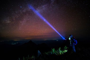 Genç adam ayakta gece gökyüzü ile dağda