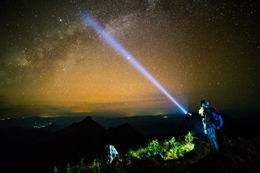 Genç adam ayakta gece gökyüzü ile dağda