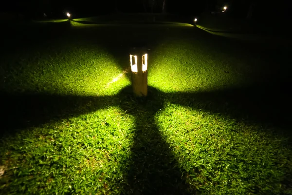 Light bulb glowing in the grass at night — Stock Photo, Image