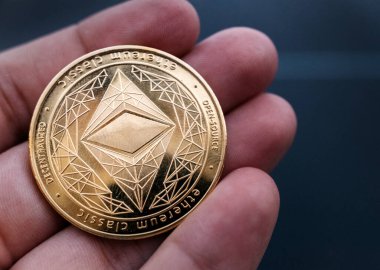 El ele tutuşan altın Eth sikkesi. Ethereum, merkezi olmayan, açık kaynaklı ve akıllıca bir kontratı olan bir blokaj zinciri. Kripto para birimi ve merkezi olmayan finans kavramı