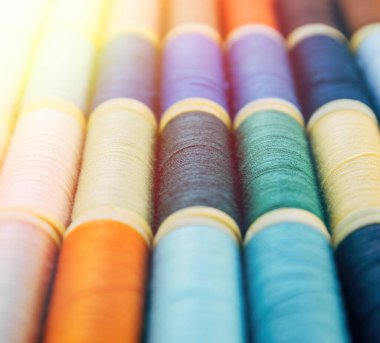 Bobinlere dikiş dikmek için renkli iplikler. Büyük renkli iplik makaraları yığını. İpin renkli iplik makaraları büyük sınıf, tekstil, arkaplan