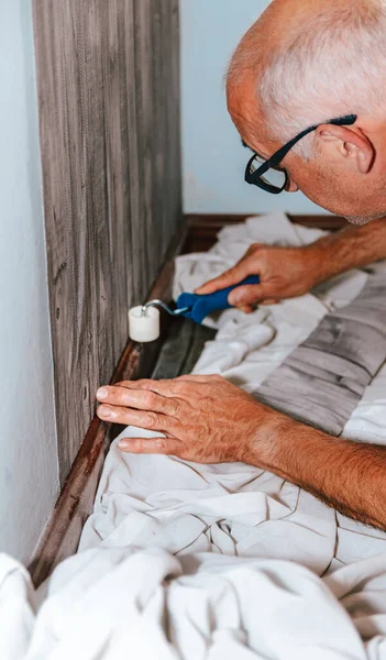 壁紙だ 男は不織布のバッキングにグレーのビニール壁紙を接着します 部屋の改装 壁紙を貼れ 家の修理 — ストック写真