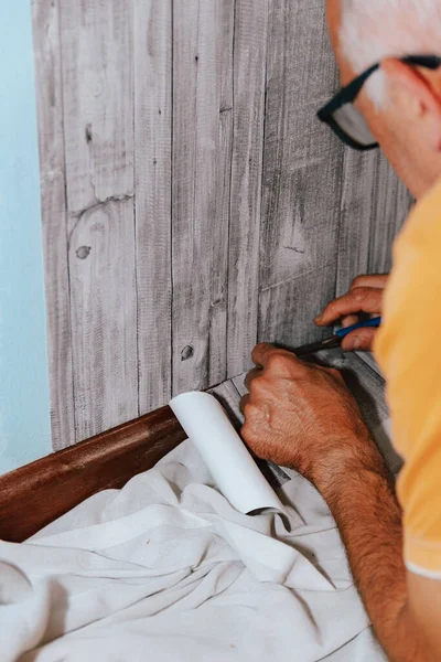 壁紙だ 男は不織布のバッキングにグレーのビニール壁紙を接着します 部屋の改装 壁紙を貼れ 家の修理 ロイヤリティフリーのストック画像