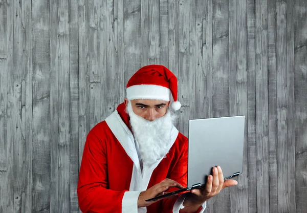 白人年轻人穿着圣诞老人的衣服 手里拿着笔记本电脑 怒气冲冲 圣诞销售概念 — 图库照片