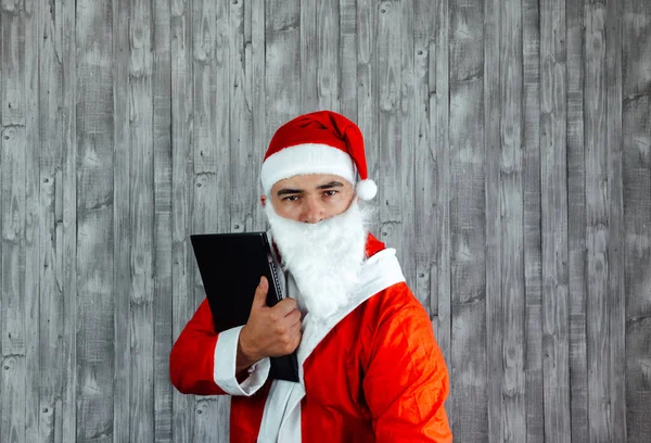 白人年轻人穿着圣诞老人的衣服 手里拿着笔记本电脑 怒气冲冲 圣诞销售概念 — 图库照片