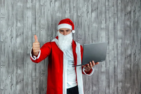 Kaukasischer Junger Mann Als Wütender Weihnachtsmann Mit Laptop Der Hand Stockfoto