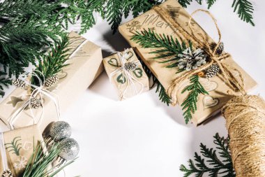 Noel arkaplanı, el yapımı hediye kutuları, ip ve çam kozalaklı süslemeler ve dal beyazı. Tatil hazırlığı..