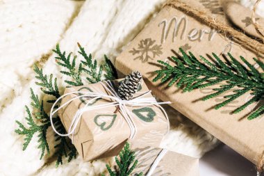 Noel arkaplanı, el yapımı hediye kutuları, ip ve çam kozalaklı süslemeler ve ahşap arka planda dallar. Tatil hazırlığı. El yapımı. Seçici odak