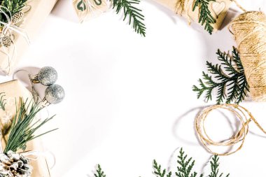 İçinde thuja dalları, çam kozalakları, el işi hediyeler ve beyaz arka planda festival süsleri olan bir Noel çerçevesi. Genel görünüm, kopyalama alanı olan düz uzanma.